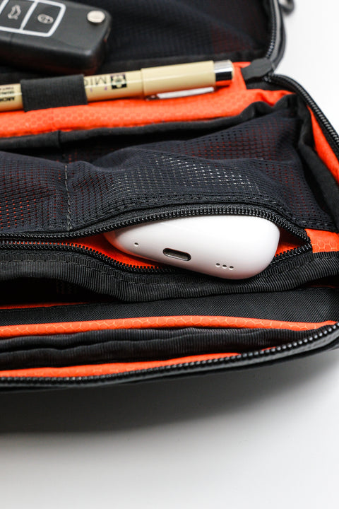 Alpha Pack interior close up showing zippered pocket with airpods case sticking out and pen in the pen holder | Color: Black VX | Size: 1.8L