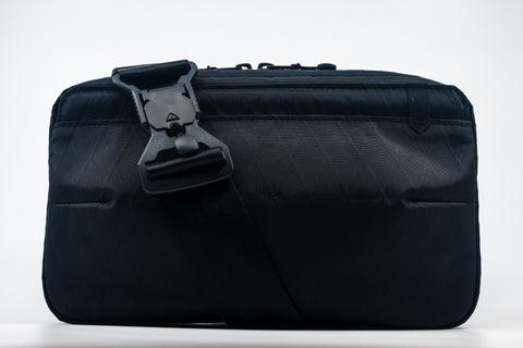 An Alpha Pack shown from the front with strap with Fidlock buckle draping over the front | Color: Black VX | Size: 2.6L