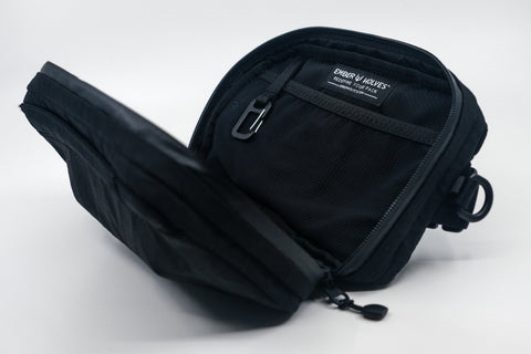 An Alpha Pack shown open and displaying a built-in carabiner and label tag  | Color: Tactical Black | Size: 1.8L