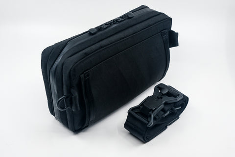 An Alpha Pack with detached strap and buckle rolled up. | Color: Tactical Black | Size: 2.6L